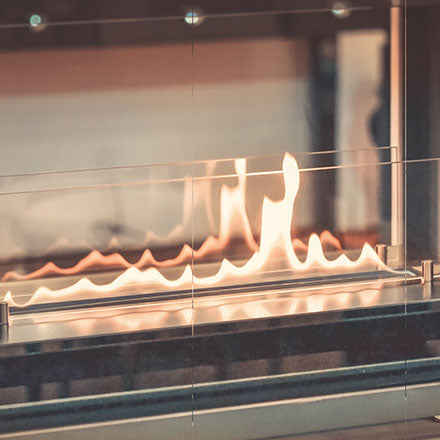 Flammen tanzen hinter einer Glasscheibe in einem modernen Kamin.